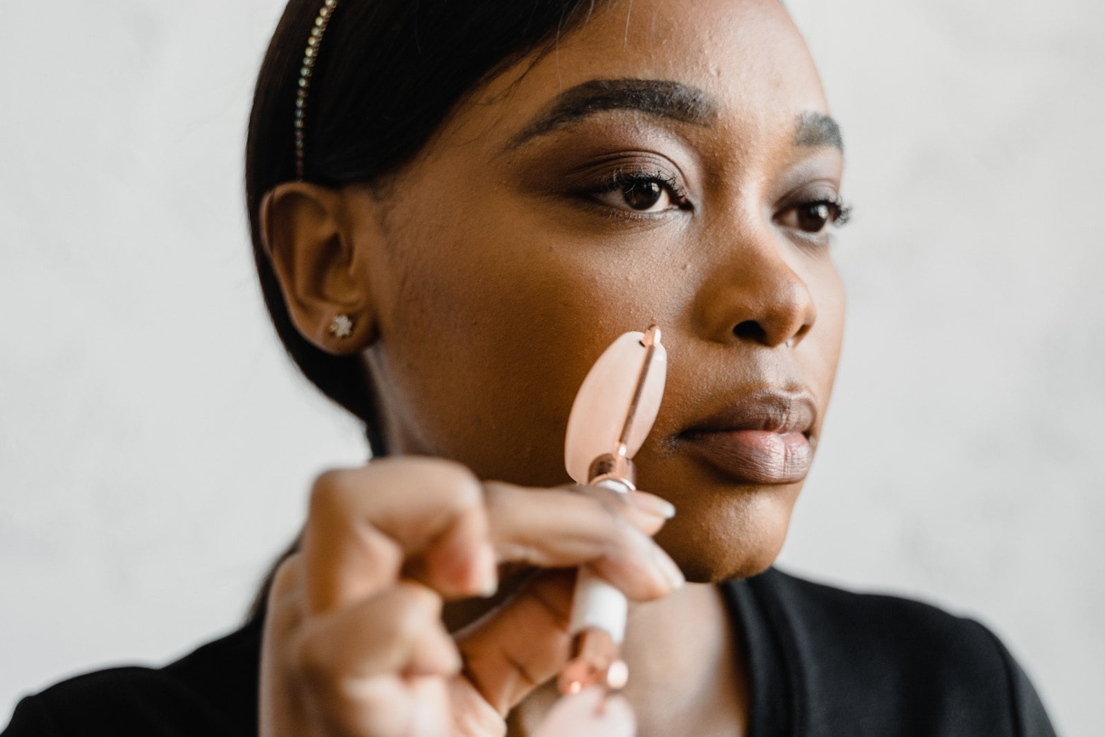 A Woman Massaging Her Face using a Jade Roller